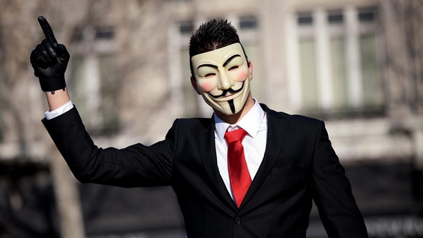 Mann im Anzug mit Guy-Fawkes-Maske, dem Symbol für die Freiheit, mit erhobenem Zeigefinger | Bild: picture-alliance/dpa