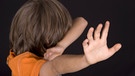 Ein Junge wehrt sich und hält sich die Arme schützend vor das Gesicht | Bild: picture-alliance/dpa