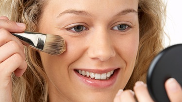 Frau schminkt sich und hält einen Spiegel in der Hand | Bild: colourbox.com