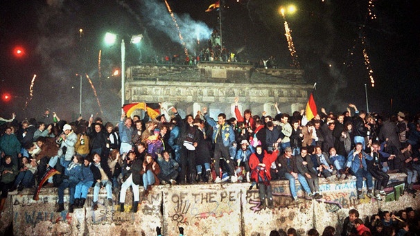 Ausgelassen feiern Ost und West an und auf der Berliner Mauer am Brandenburger Tor Silvester 1989  | Bild: picture-alliance/dpa