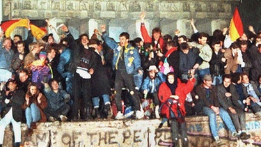 Ausgelassen feiern Ost und West an und auf der Berliner Mauer am Brandenburger Tor Silvester 1989  | Bild: picture-alliance/dpa