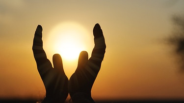Symbolbild: Zum Gebet erhobene Hände, im Hintergrund ein Sonnenuntergang | Bild: colourbox.com