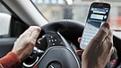 Smartphone in der Hand eines Autofahrers | Bild: picture-alliance/dpa