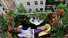 Frau liest auf einem mit Blumen geschmückten Balkon | Bild: picture-alliance/dpa
