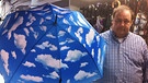 Regenschirme Schirme Schirmgeschichten - Meinrad Aumüller hällt einen Wetterschrim mit Himmel voller Wolken in die Höhe | Bild: Hannelore Fisgus / BR