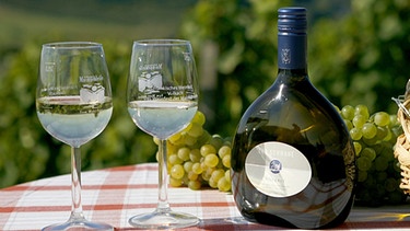 Ein Bocksbeutel mit Weingläsern und Weintrauben | Bild: picture-alliance/dpa