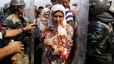 Syrische Flüchtlinge, bewacht von türkischen Polizisten | Bild: picture-alliance/dpa