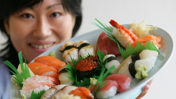 Eine Japanerin präsentiert einen Sushi-Teller. | Bild: picture-alliance/dpa