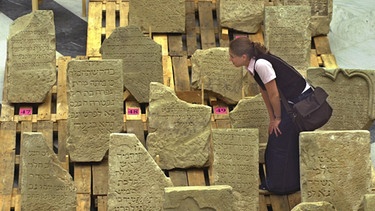 Eine Studentin betrachtet einen jüdischen Grabstein in der Würzburger Universität. | Bild: picture-alliance/dpa