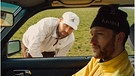 Ein Mann sitzt mit gelbem Fleecepulli und Mütze auf dem Beifahrersitz. Ein anderer Mann ist durch das geöffnete Fenster der Beifahrertür zu sehen. Er trägt einen weißen Pulli.  | Bild: Ferge x Fishermann Instagram 