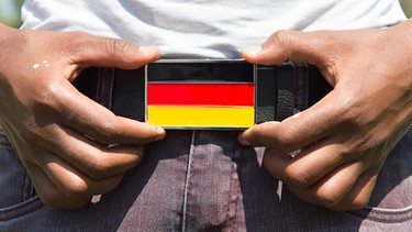 Ein Asylbewerber aus Eritrea trägt eine Gürtelschnalle in Form einer Deutschlandflagge | Bild: picture-alliance/dpa