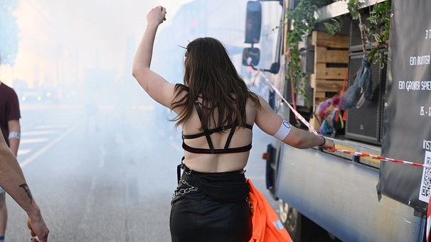Eine Frau tanzt auf der Straße. Sie geht neben einem Wagen her und hebt den linken Arm in die Luft.  | Bild: picture alliance / SZ Photo | Stephan Rumpf