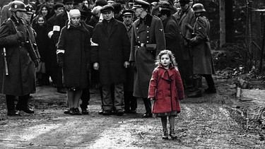 Mädchen im roten Mantel steht vor Männern | Bild: picture-alliance/dpa