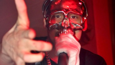Der Rapper Sido hat eine Maske auf und schaut auffordernd direkt in die Kamera.  | Bild: ZB | Andreas Lander