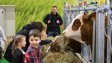 Kinder füttern Kühe mit Heu auf dem Erlebnisbauernhof auf der Grünen Woche in Berlin | Bild: 2016 Messe Berlin 