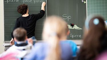 Eine Lehrerin schreibt in einer Grundschule Wörter mit «Sp» am Anfang an eine Tafel. | Bild: dpa-Bildfunk/Sebastian Gollnow