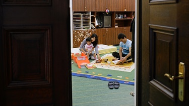 Familie im Kirchenasyl spielend am Boden | Bild: BR