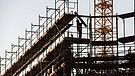 Ein Bauarbeiter hebt auf einer Baustelle ein Brett in die Höhe | Bild: picture-alliance/dpa/Paul Zinken