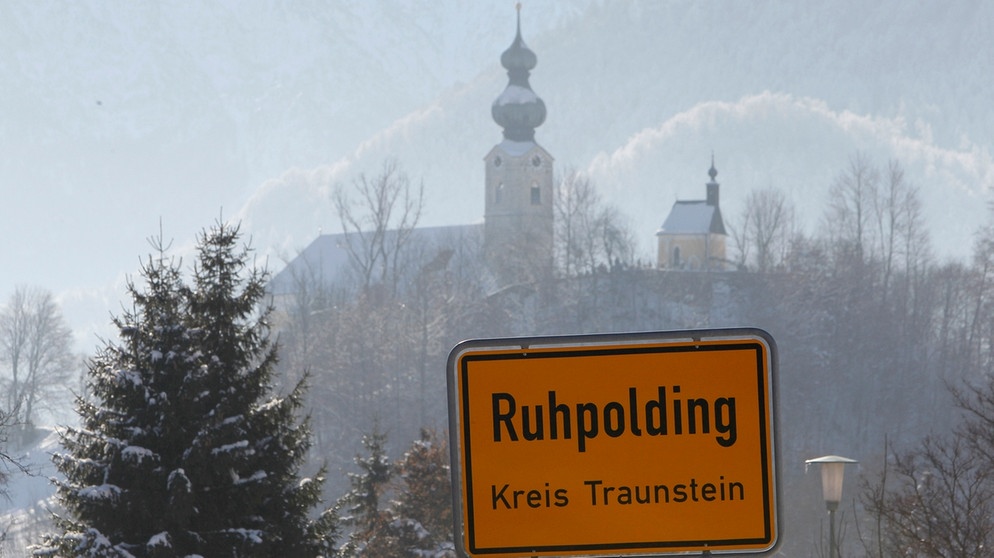 Das Ruhpoldinger Ortsschild mit der Pfarrkirche St. Georg im Hintergrund | Bild: picture-alliance/dpa
