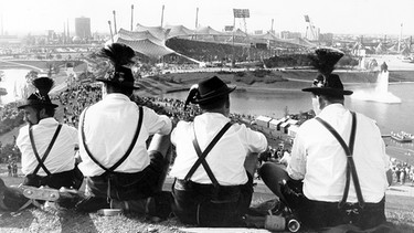 Zuschauer in bayerischer Tracht blicken vom Olympiaberg auf das Olympiastadion | Bild: Süddeutsche Zeitung Photo / Oswald Baumeister