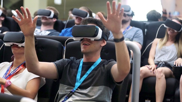 Fachbesucher machen auf der Spielemesse Gamescom mit der VR-Brille (Virtual Reality) eine vierdimensionale Achterbahnfahrt.  | Bild: picture-alliance/dpa