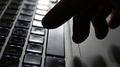 Ein Mann deutet mit seinem Finger auf eine Computertastatur.  | Bild: picture-alliance/dpa