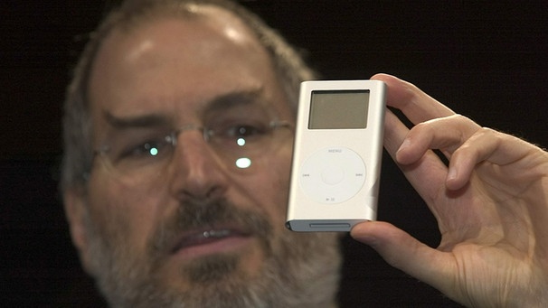 iPod Mini: Der mittlerweile verstorbene, damalige Apple-Chef Steve Jobs stellt im Januar 2004 den iPod Mini vor. Geräte wie der Kreditkartengroße mp3-Player machen Podcasts zu einem attraktiven Web-Inhalt für unterwegs. | Bild: picture-alliance/dpa