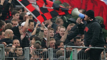 Mit einem Megafon sorgt ein Nürnberger Fan in seinem Fanblock beim Auswärtsspiel in Frankfurt für Stimmung (5.4.2008) | Bild: picture-alliance/dpa