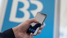 Smartphonenutzung mit BR Logo im Hintergrund | Bild: BR/Philipp Kimmelzwinger