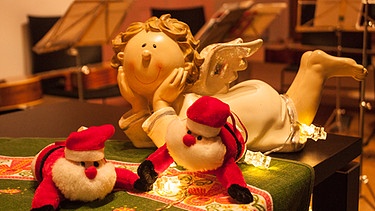 Ein Weihnachtsengel und zwei Weihnachtsmänner als Dekoration auf dem Klavier bei der Sprecherstunde Abensberg | Bild: BR/Michael Atzinger