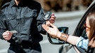 Frau übergibt einen Alkoholtester der Polizei | Bild: mauritius images / RossHelen editorial / Alamy / Alamy Stock Photos
