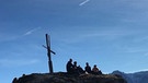 Wanderer sitzen auf dem Gipfel vor einem Gipfelkreuz | Bild: BR; Elisabeth Tyroller