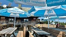 Fockenstein: Hier genießen die Gäste leckeres Essen unter großen blauen Sonnenschirmen | Bild: BR/Marlene Thiele