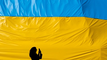Eine Frau fotografiert ein Transparent in den Farben der ukrainischen Flagge | Bild: dpa-Bildfunk/Deml Ondøej