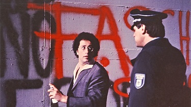 Effendi (Robert Giggenbach) wird beim Sprayen an eine Hauswand von einem Polizisten entdeckt. | Bild: BR/Tellux-Film
