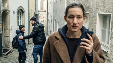 Frederike (Marie Leuenberger) erschreckt sich bei einem Telefonat mit Mia vor zwei Arabern. | Bild: ARD Degeto/BR/Hager Moss Film GmbH/Hendrik Heiden