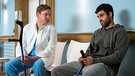 Dr. Marc Lindner (Christian Beermann, links) findet einen Draht zu seinem Patienten Aziz Rahmani (Deniz Arora, rechts). Mit seinen Worten trifft er nicht nur bei ihm genau ins Schwarze. | Bild: ARD/Jens Ulrich Koch