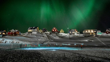 Polarlicht über Dorf auf Grönland. Das Fußballspiel an der Küste Grönlands wird auch vom Polarlicht erhellt. Satellitenbilder zeigen uns das Phänomen noch einmal ganz anders. | Bild: BBC/BR/NDR