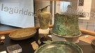 In Irlbach in Niederbayern ist die erste jemals in Deutschland gefundene Situla, ein spezielles Bronzegefäß (hinten rechts), präsentiert worden.  | Bild: BR/Veronika Meier