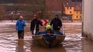 Personen mit Boot laufen durch überflutete Straße | Bild: BR