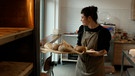 Frau hält Backblech mit gebackenenen Broten | Bild: BR