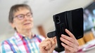Eine Seniorin versendet Nachrichten über ein Smartphone. | Bild: picture alliance/dpa | Sina Schuldt
