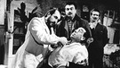Mit Genuss beobachtet Peppone (Gino Cervi, Mitte), wie sein Lieblingsfeind Don Camillo (Fernandel, sitzend) versucht, sich dem Zahnarzt zu widersetzen. | Bild: ARD Degeto/BR