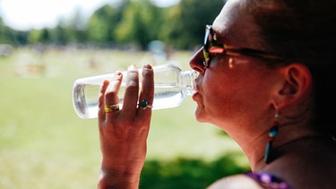 Eine Frau trinkt Wasser aus einer Flasche. | Bild: BR/Julia Müller
