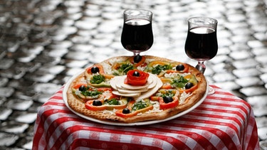Tisch Rotweingläsern und Pizza | Bild: picture-alliance/dpa