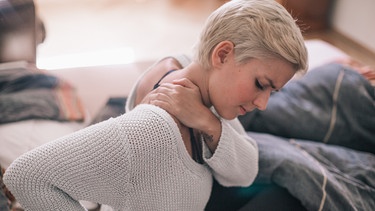 Eine junge Frau mit Rückenschmerzen im Bett. | Bild: BR/Johanna Schlüter