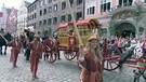 Eine Kutsche begleitet von Frauen in historischen Kleidern in einer Altstadt | Bild: BR