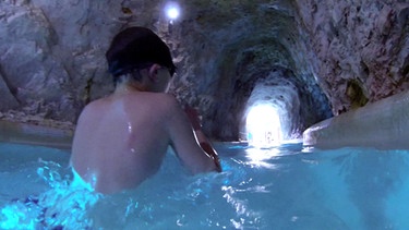 Ein Junge schwimmt in einem Tunnel | Bild: BR