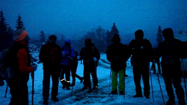 Eine Gruppe von Wanderer im leichten Schnee beim Morgengrauen | Bild: BR