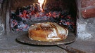 Ein Brotlaib wird aus einem Steinofen geholt | Bild: BR